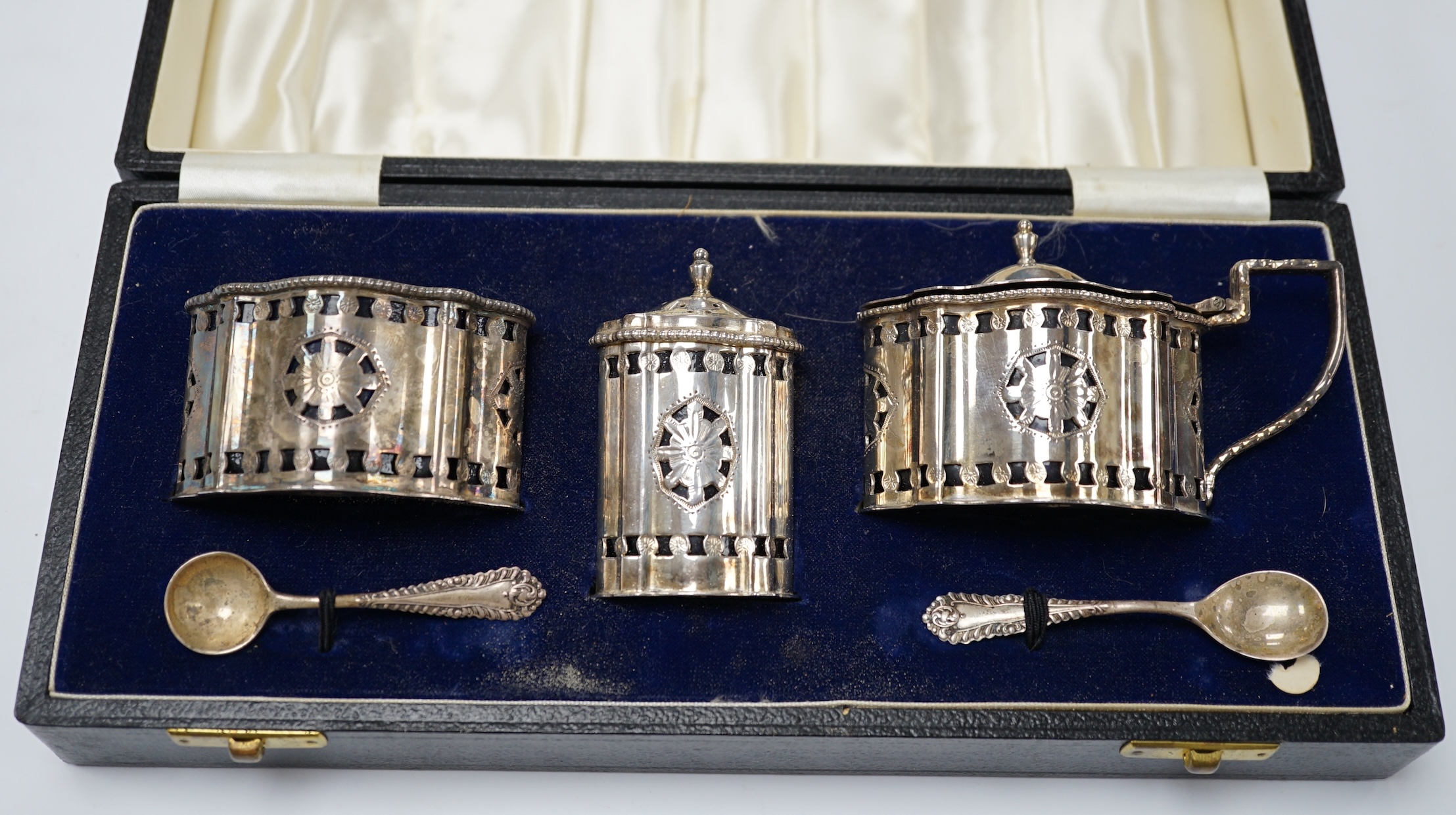 A cased 1970's silver three piece condiment set and two spoons by A. Chick & Sons, London, 1972, with blue glass liners (chipped). Condition - poor to fair